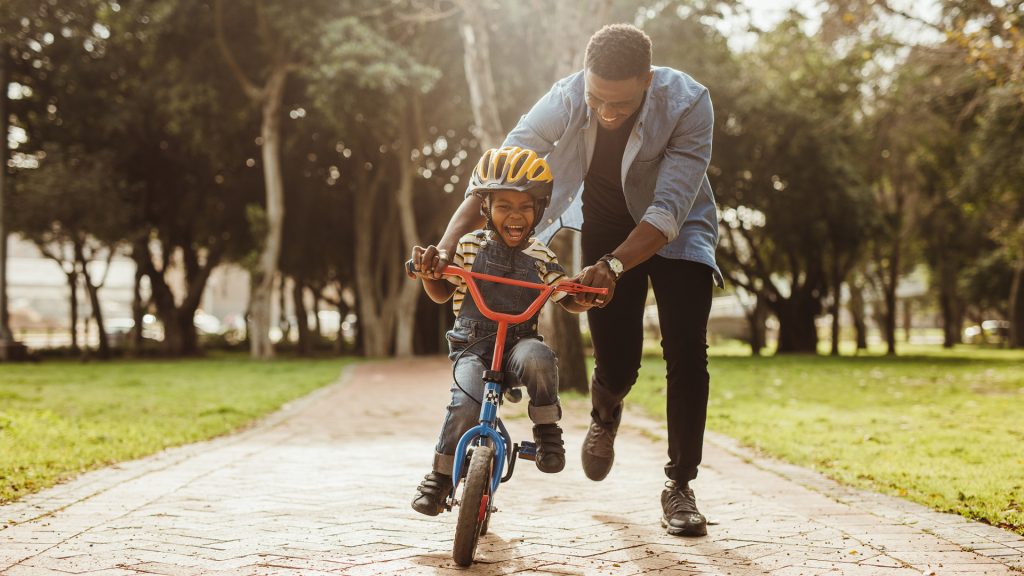 Father teaching his son cycling at park