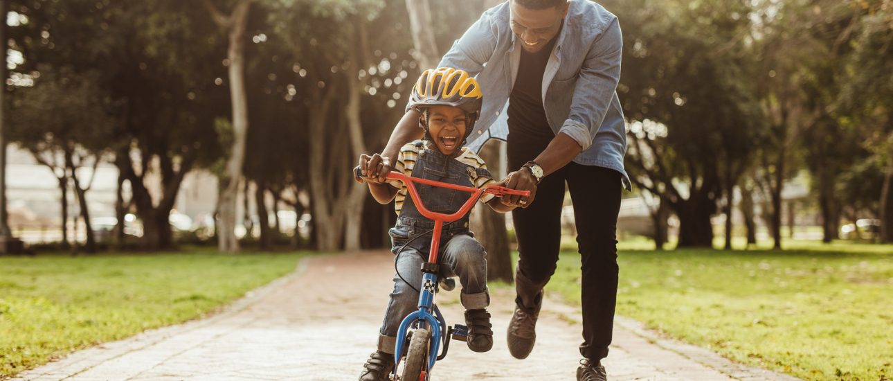 Father teaching his son cycling at park