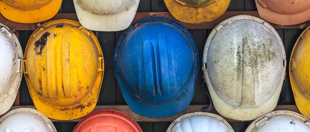 Old and worn construction helmets on wall