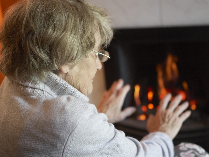 Senior citizen keeping warm by the fire